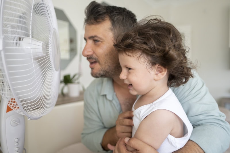 Dad and daughter in fron of a fan.
