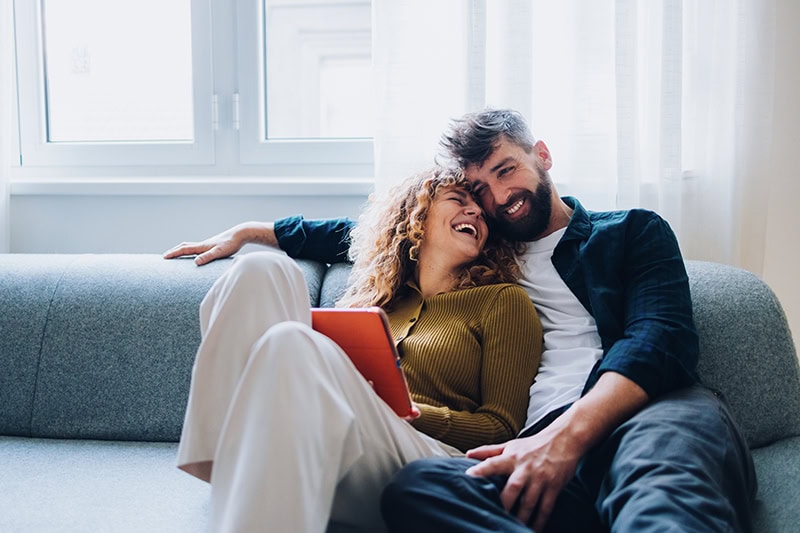 A couple sitting on a couch enjoying life.