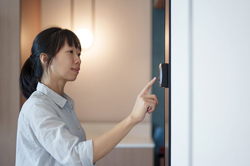 A women setting her thermostat.