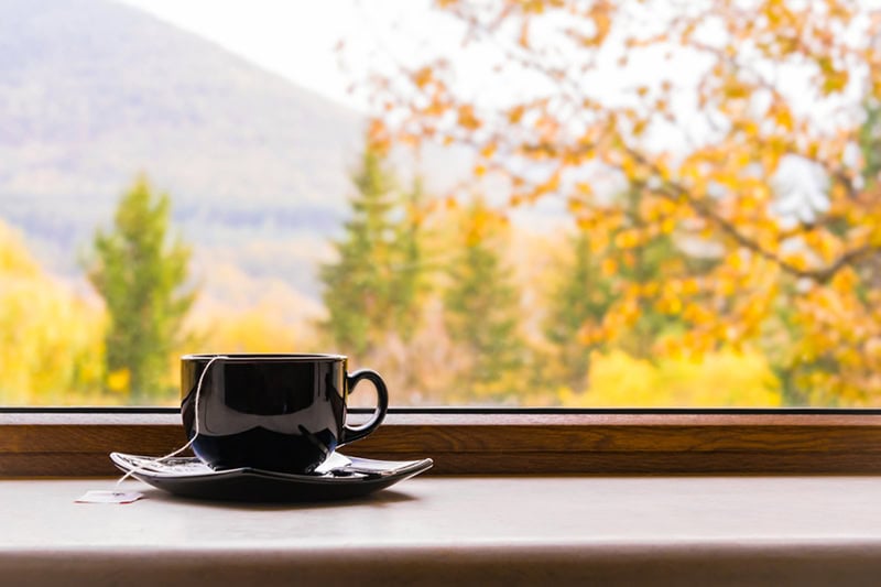 A cup of cofee in front of a window.