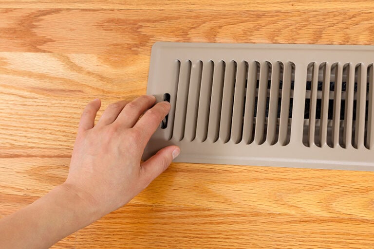 A person closing an HVAC vent.